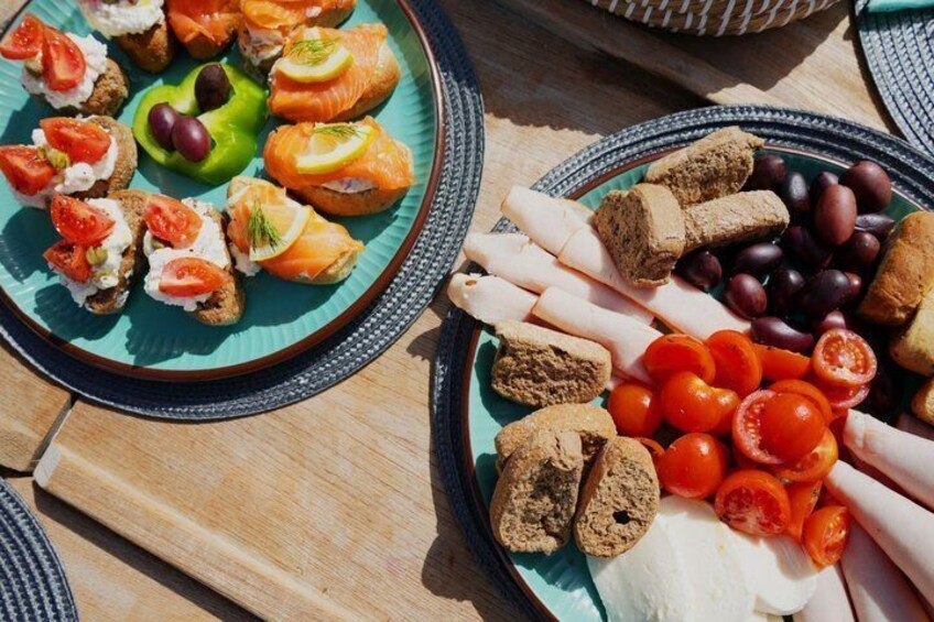 A variety of food items on plates, including salmon, tomatoes, olives, and bread. 5