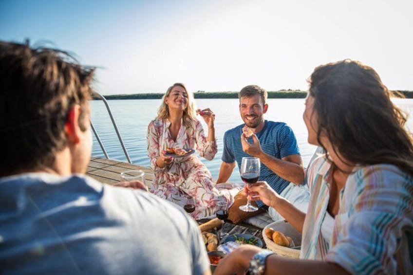 A group of people on a boat, enjoying a meal and drinks. 1
