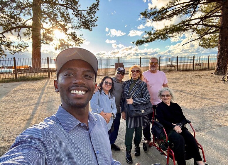 A group of people in a park with trees and a fence in the background. 3