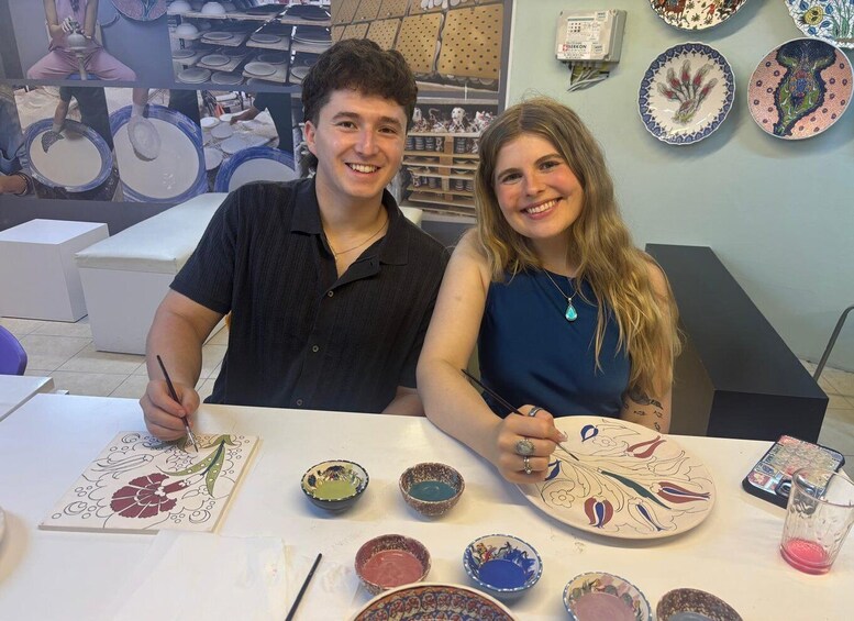 Two people at a pottery workshop with various bowls and plates. 5