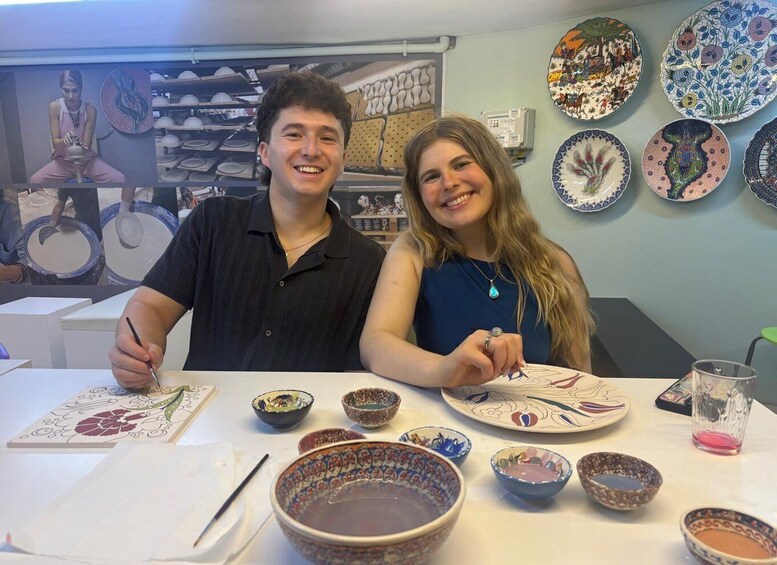Two people at a pottery workshop with various bowls and plates on display. 3