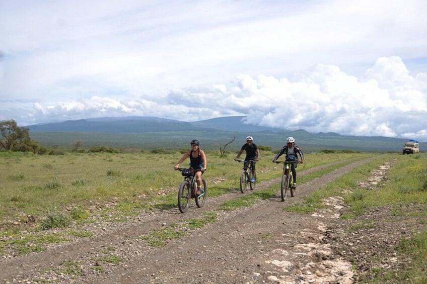 Three cyclists on a dirt path with a mountainous landscape in the background. 4
