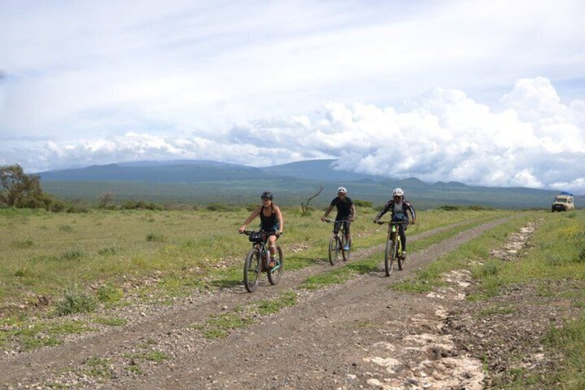 Three cyclists on a dirt path with a mountainous landscape in the background. 4