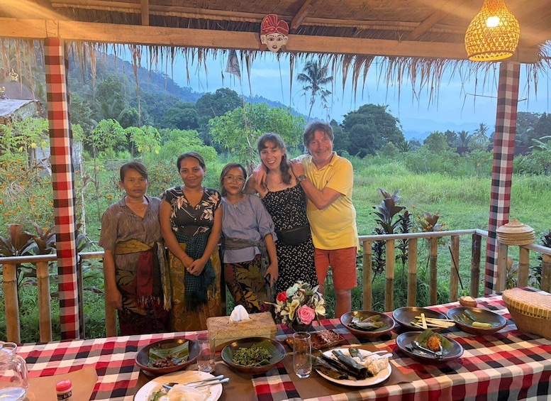 A group of people dining outdoors with a checkered tablecloth, surrounded by lush greenery and a scenic view. 5