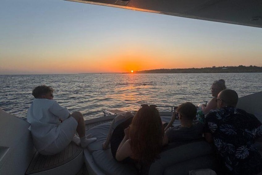 A sunset over water with people on a boat. 3