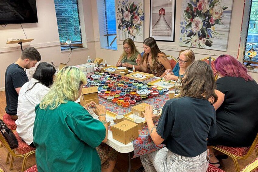 A group of people seated around a table with various items and boxes. 4