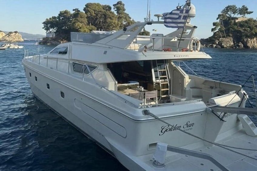 A white yacht named 'Golden Sun' with a cabin and deck area, docked near a rocky coastline with trees. 3