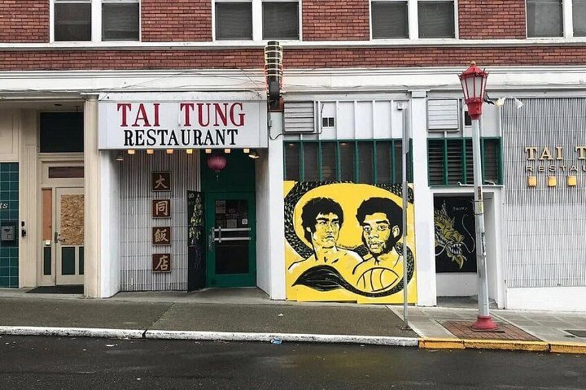 A storefront with a sign reading 'TAI TUNG RESTAURANT' and a mural of two figures. 3