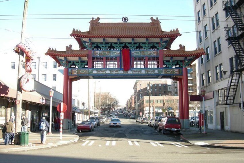 A street with a traditional Chinese archway, cars, and buildings. 1