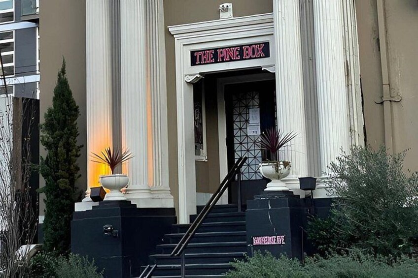 A building with a sign reading 'THE PINE BOX' and a staircase leading to the entrance. 2