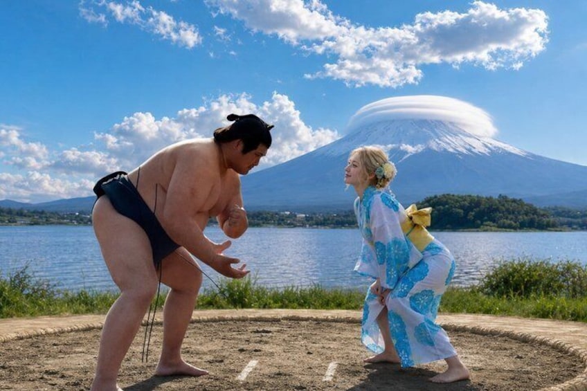 A sumo wrestler and a person in a kimono by a lake with a mountain in the background. 1