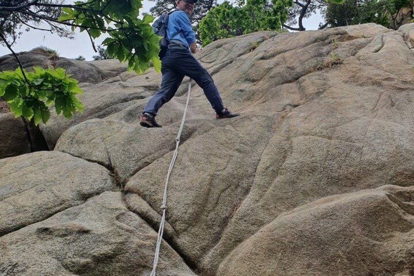 A person climbing a large rock formation with a rope. 5