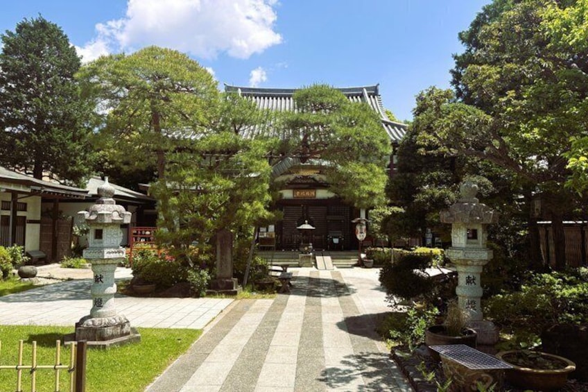 A traditional Japanese temple with a stone lantern, a stone pagoda, and a well-maintained garden. 1