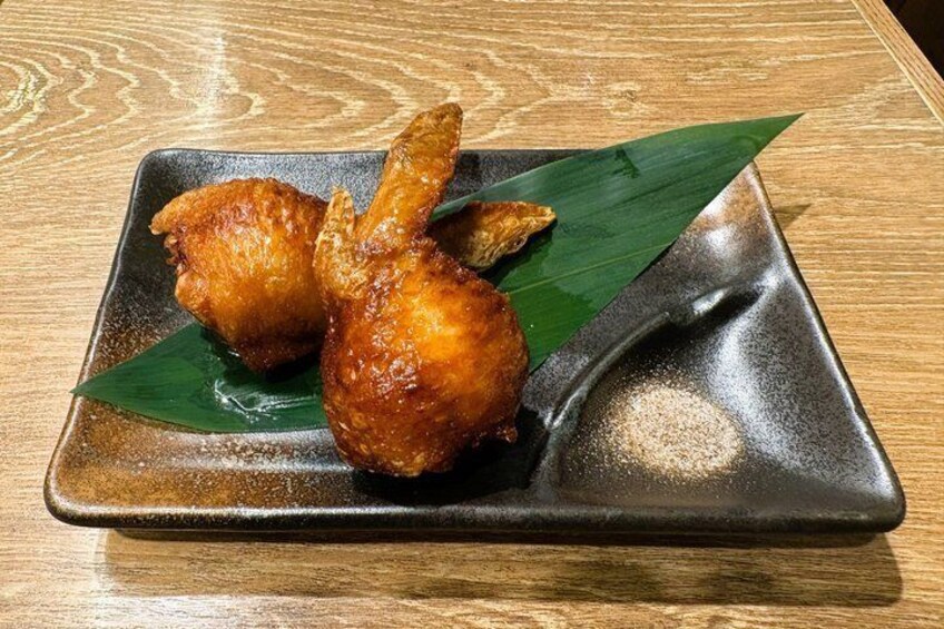 A plate of fried chicken with a green leaf garnish on a dark ceramic plate. 5