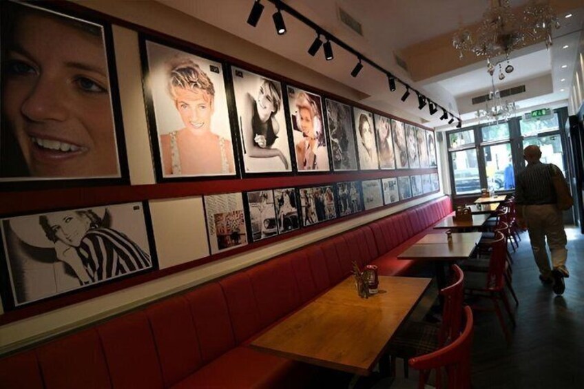 A restaurant with red booths and tables, a wall of framed pictures, and a chandelier. 5