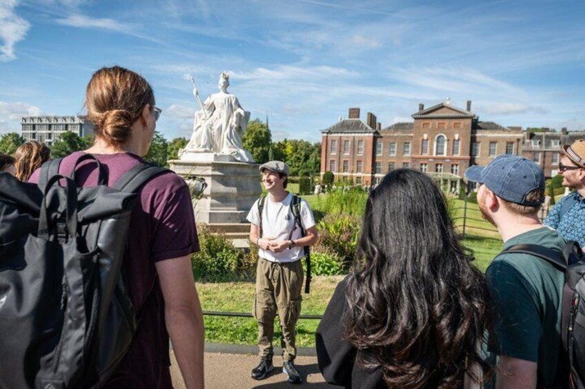 A group of people standing in a park with a statue and a large building in the background. 2