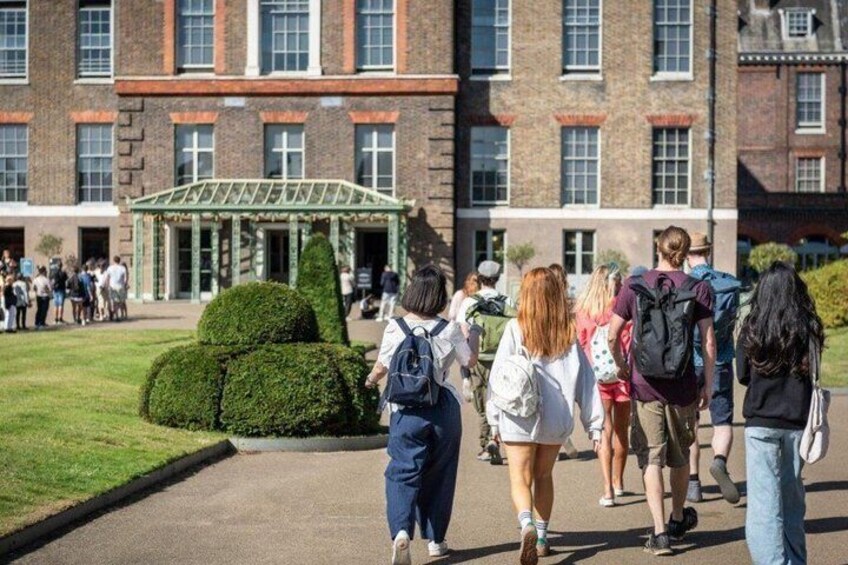 A group of students walking towards a building with a green entrance and a well-maintained lawn. 3