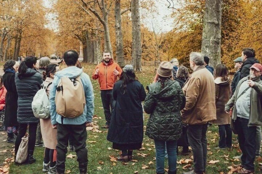 A group of people standing in a park with autumn-colored trees. 4