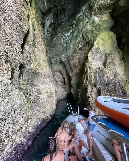 A cave with a water body, a boat, and people sitting on the boat. 5