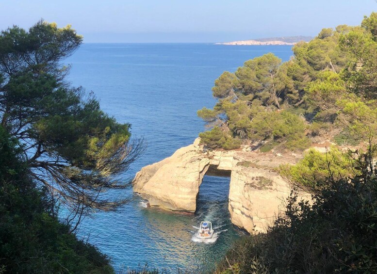 A coastal landscape with a rocky arch and a boat navigating through a narrow waterway. 2