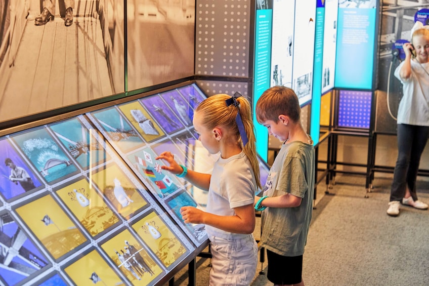 Two individuals interacting with a digital display featuring various images. 1