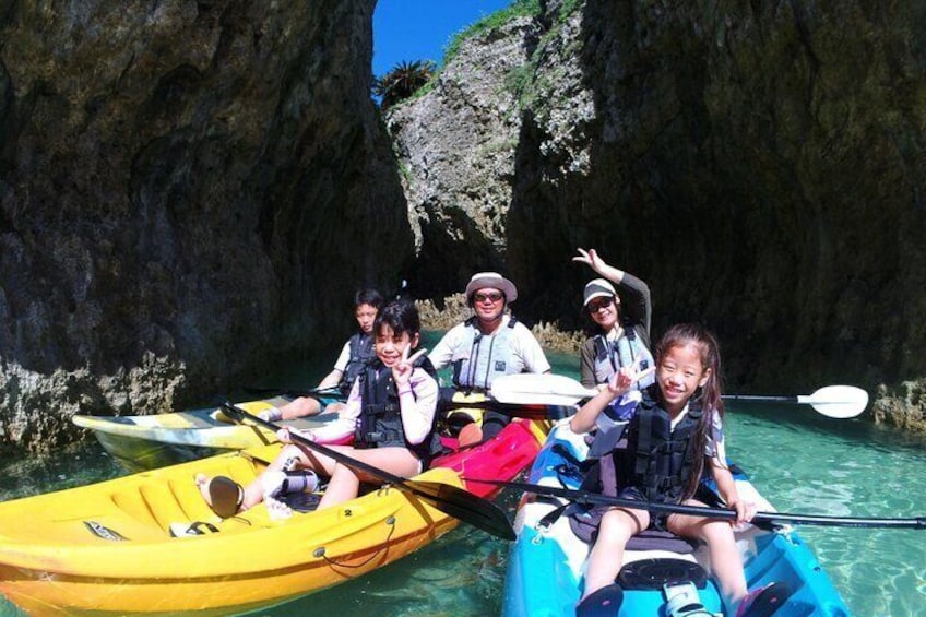 People in kayaks on a river with rocky cliffs in the background. 1