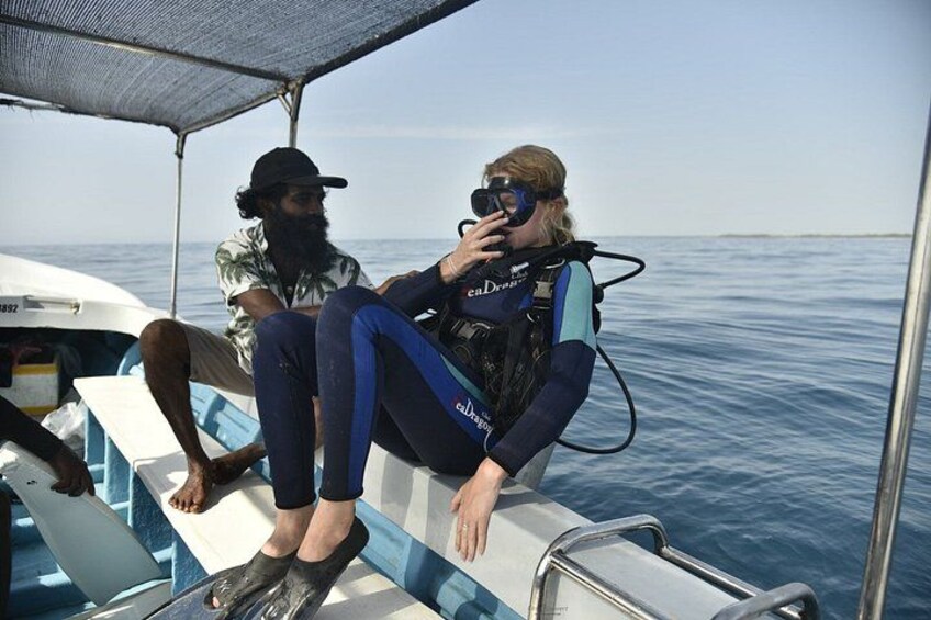 Two people on a boat, one wearing a diving suit and the other in casual clothing. 4