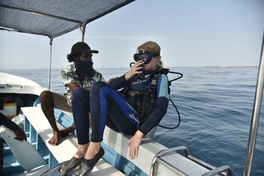 Two people on a boat, one wearing a scuba diving suit, and the other in casual attire. 4