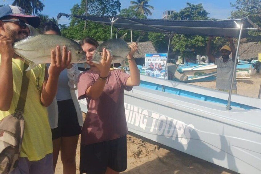 A group of people holding fish near a boat with a sign that reads 'FISHING TOURS.' 3