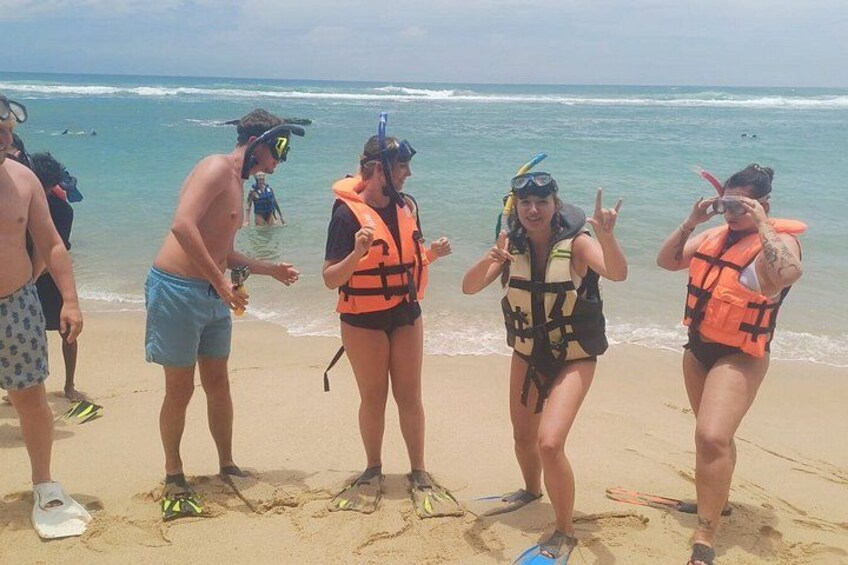 A beach with people wearing life jackets and snorkeling gear. 2