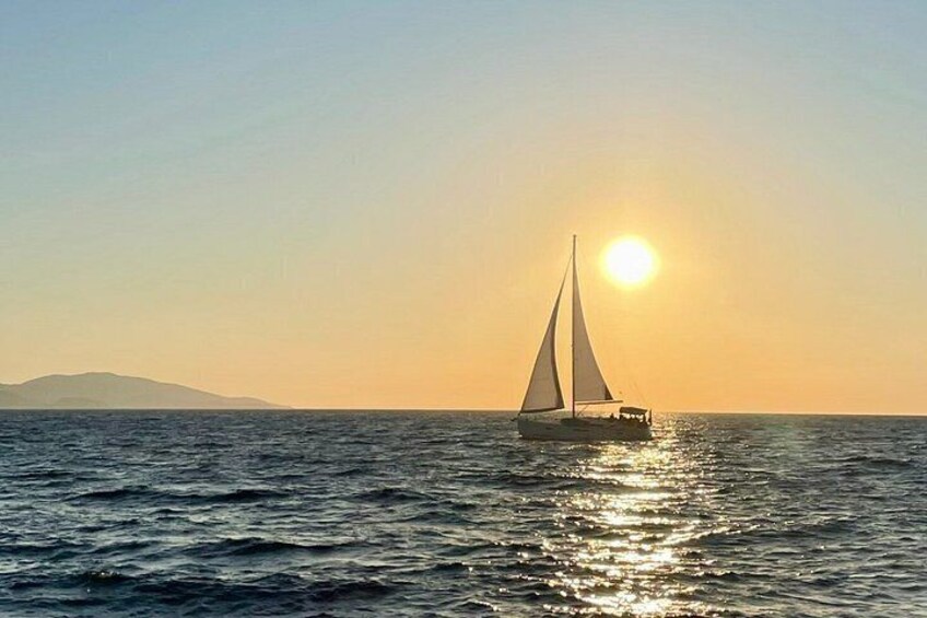 Una barca a vela su acque calme con il sole al tramonto sullo sfondo. 4