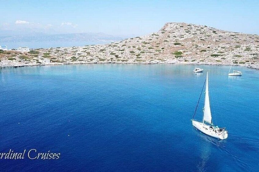 Una barca a vela su un mare calmo, con un'isola rocciosa sullo sfondo. 1