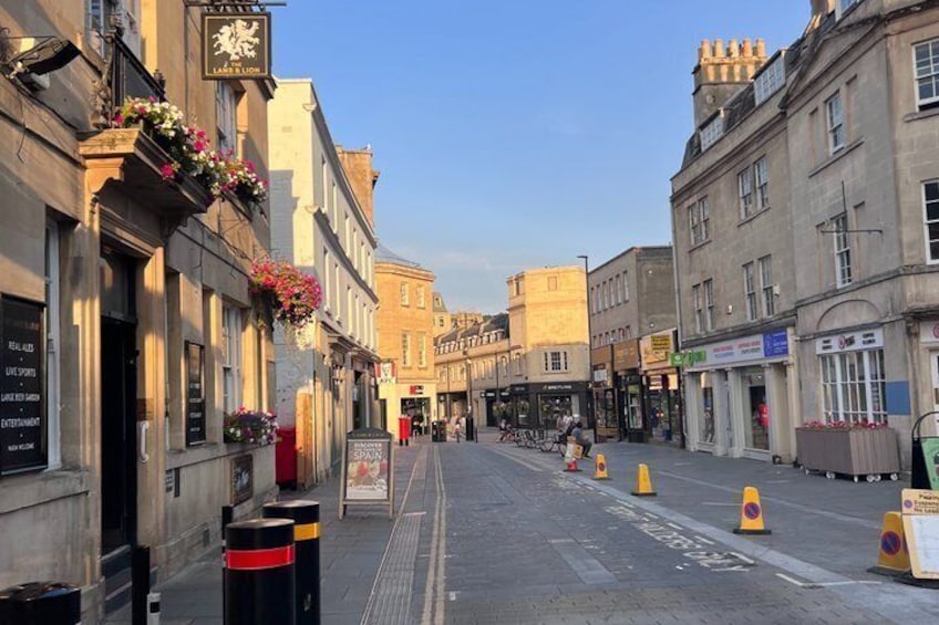 A street with buildings, bollards, and a cyclist. 3