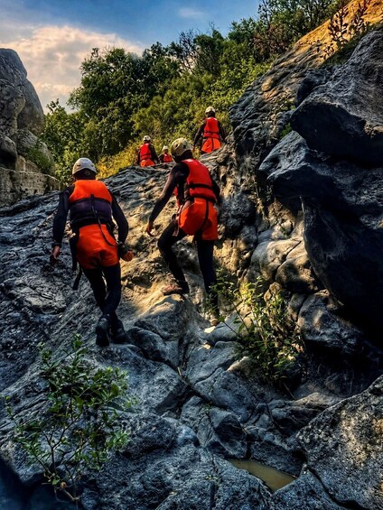 A group of people hiking on rocky terrain with vegetation. 1