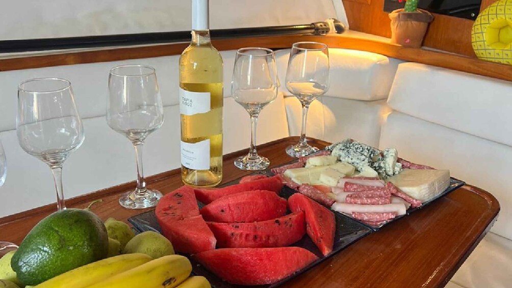 A tray with fruits, cheese, and a bottle of white wine on a boat. 2