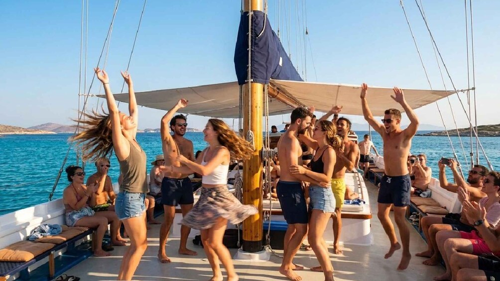 A group of people dancing on a boat with the sea and a clear sky in the background. 3