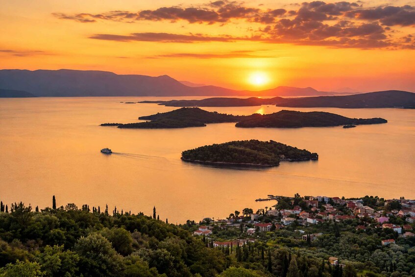 A sunset over a lake with islands, a boat, and a coastal town. 3
