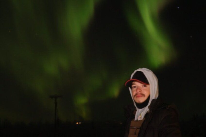 A person standing outdoors at night with the aurora borealis in the background. 2