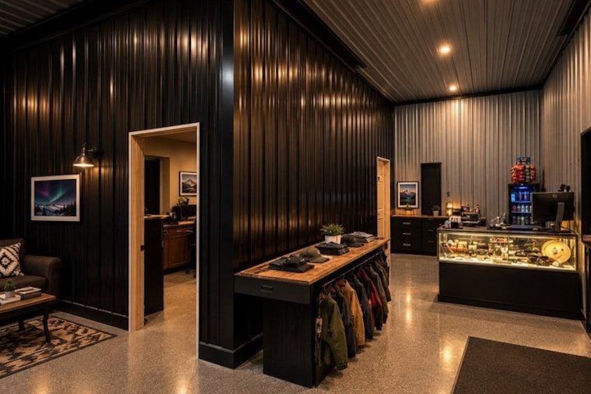 A room with dark wooden walls, a glass display case, and a bench with jackets. 4