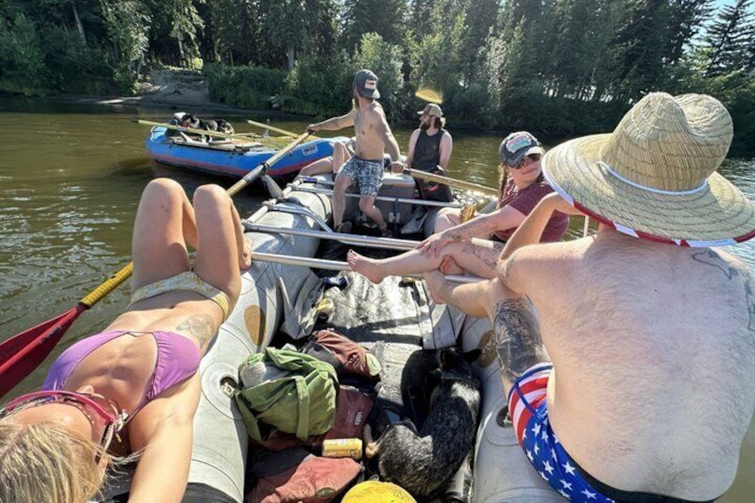 A group of people on a boat with a forested riverbank in the background. 1