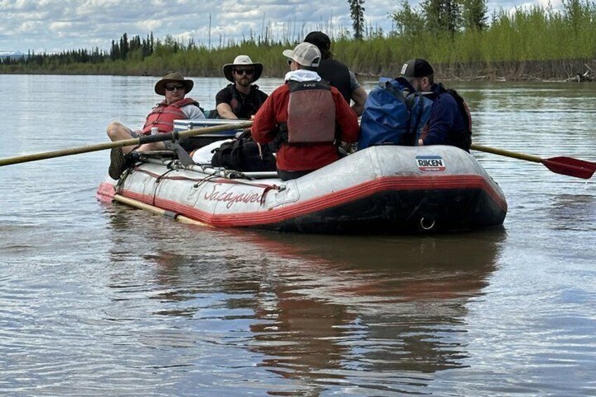 A group of people in a white and red inflatable raft on a calm body of water. 3