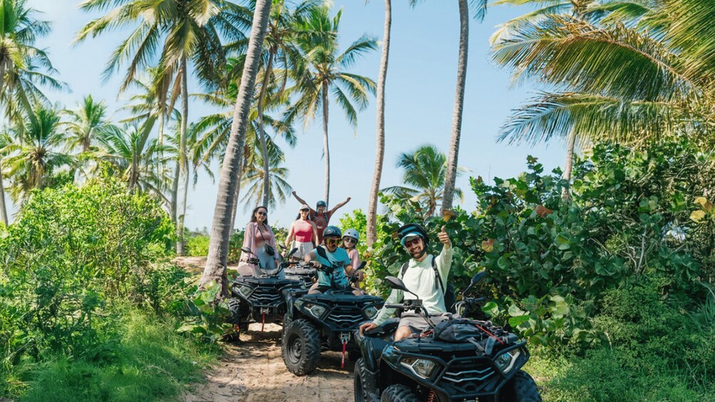 A group of people on ATVs in a tropical setting with palm trees. 3