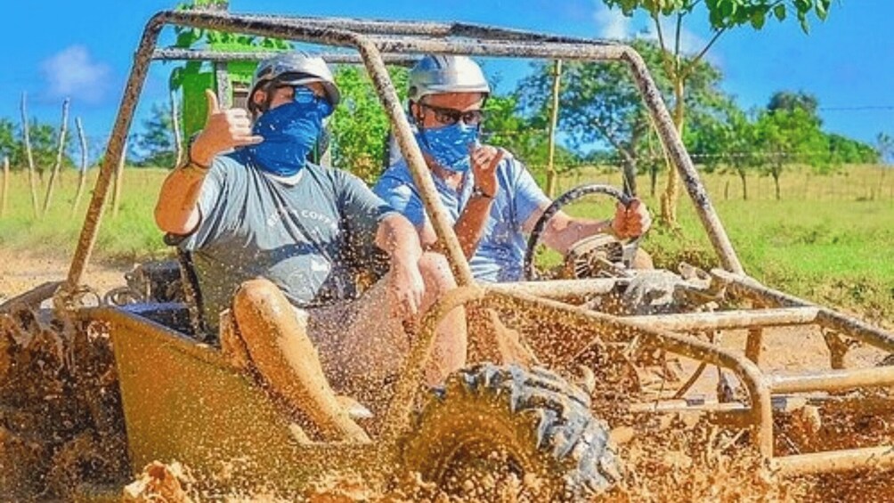 Two people in a vehicle with mud splashing around, indicating off-road driving. 4