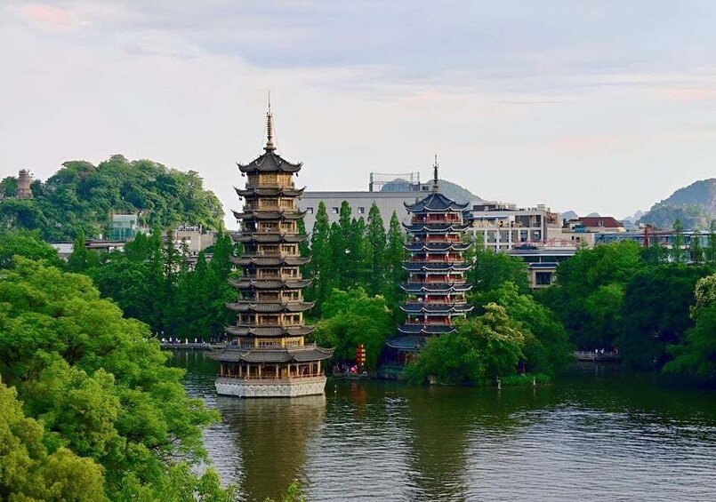 A traditional pagoda-style tower by a lake surrounded by lush greenery. 1