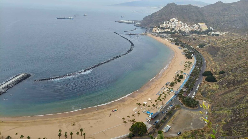 A coastal landscape with a beach, a road, and a distant town. 5