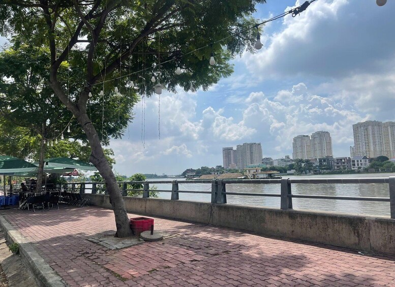 A riverside walkway with brick paving, a tree, and a row of buildings in the background. 3