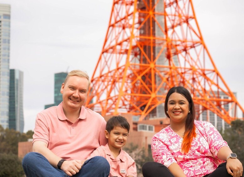A family of three sitting in front of a large orange Ferris wheel. 2