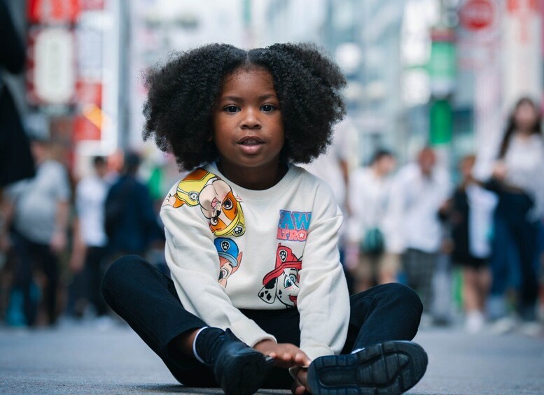 A child sitting on the ground with a white shirt featuring cartoon characters and the text 'LAW INTRO.' 4