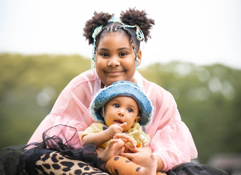A person in a pink dress holding a baby in a blue hat. 5