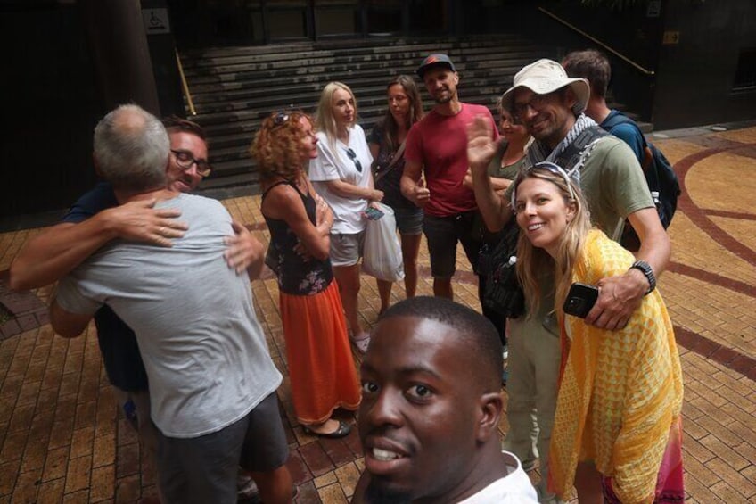 A group of people standing on a brick-paved area with steps in the background. 1